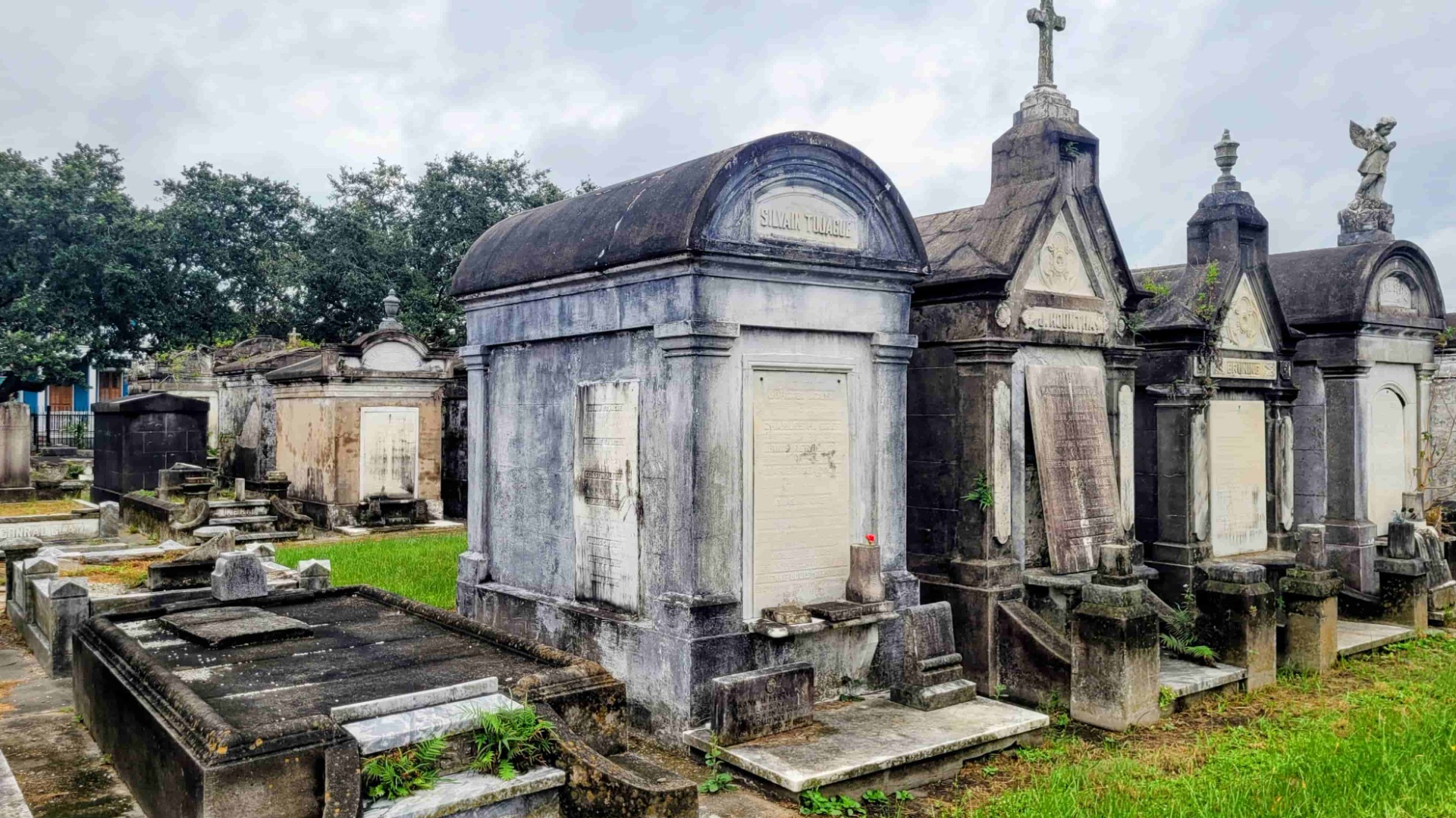 Historischer Friedhof mit steinernen Grabmälern, Mausoleum mit Kuppel und Kreuz, umgeben von Bäumen und Gras.